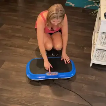 Person kneeling on the floor, pointing at a blue exercise platform.