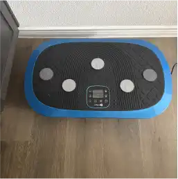 A blue and black vibration plate exercise machine sitting on a hardwood floor.