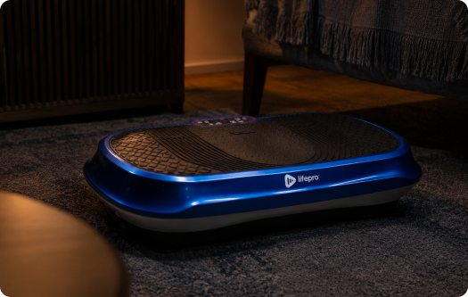 A blue and black Lifepro vibration plate sitting on a dark grey carpet in a living room.