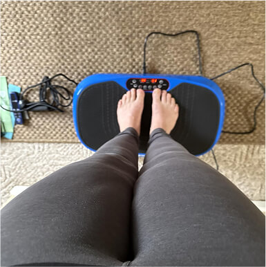 Person standing on a blue vibration plate with display and controls.
