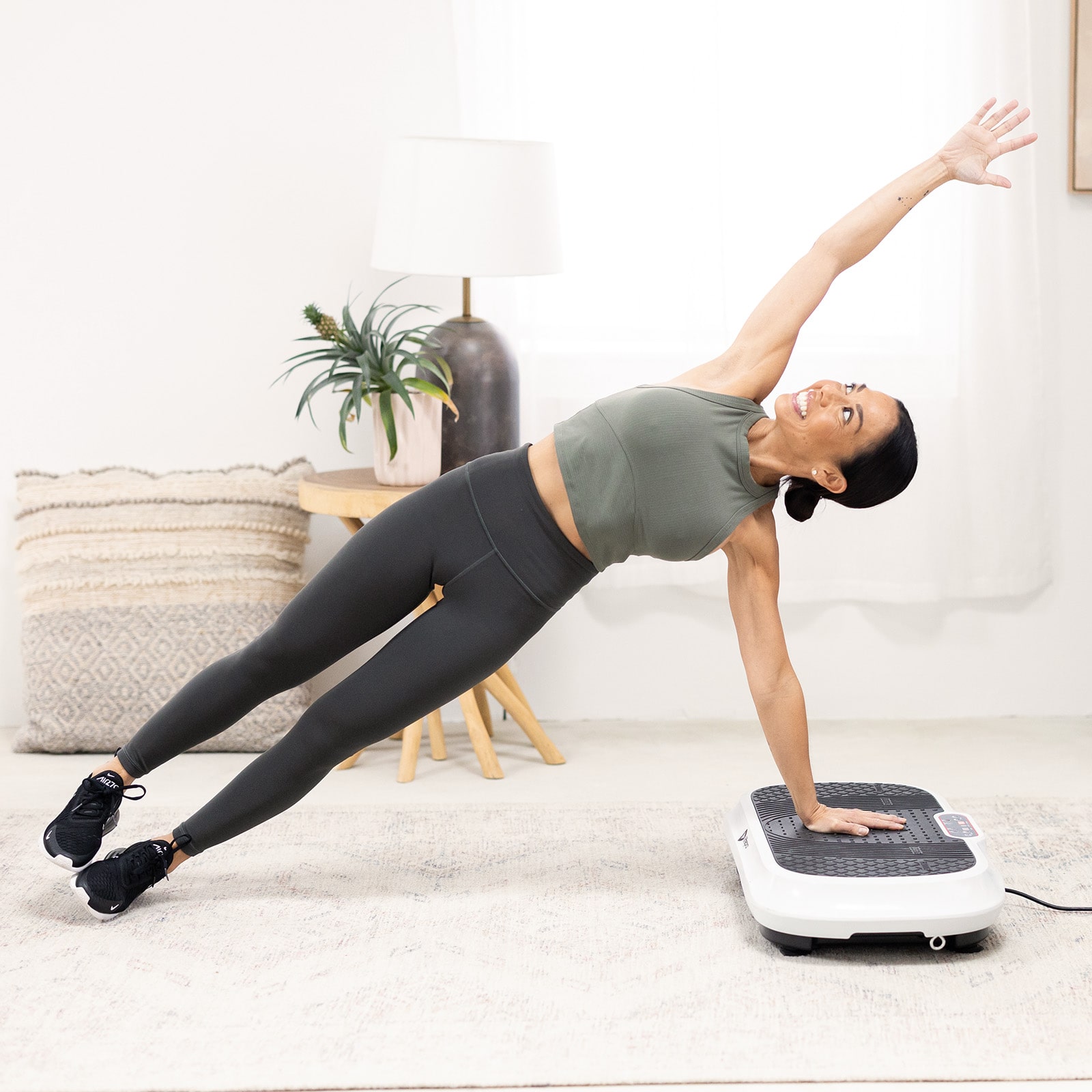 Person doing a side plank on a vibration plate in a living room.