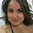 A close-up photo of a woman with wavy brown hair looking forward with a slight smile.