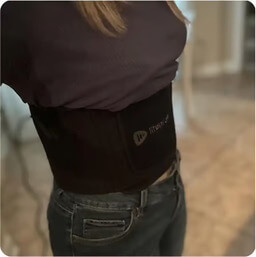 A person viewed from the side wearing a wide black waist wrap under a dark shirt and jeans.