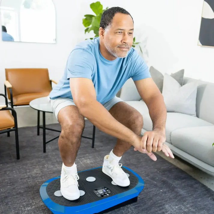 Man exercising on a vibration plate in a living room.