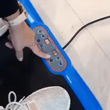 Person adjusting controls on a blue treadmill with white sneakers visible.