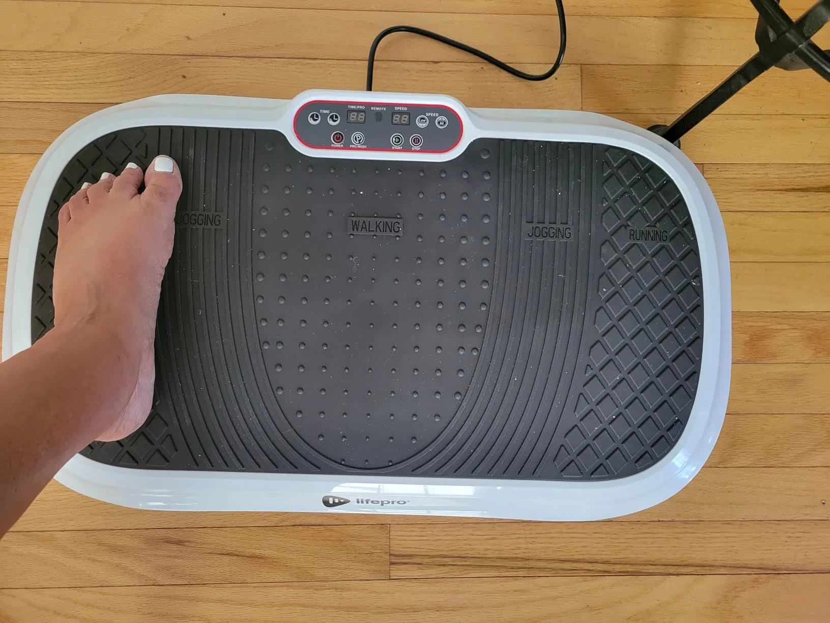 A foot on a vibrating exercise platform with control panel.