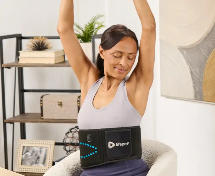 A woman stretches in a chair while wearing a black Lifepro waist belt with blue lights.