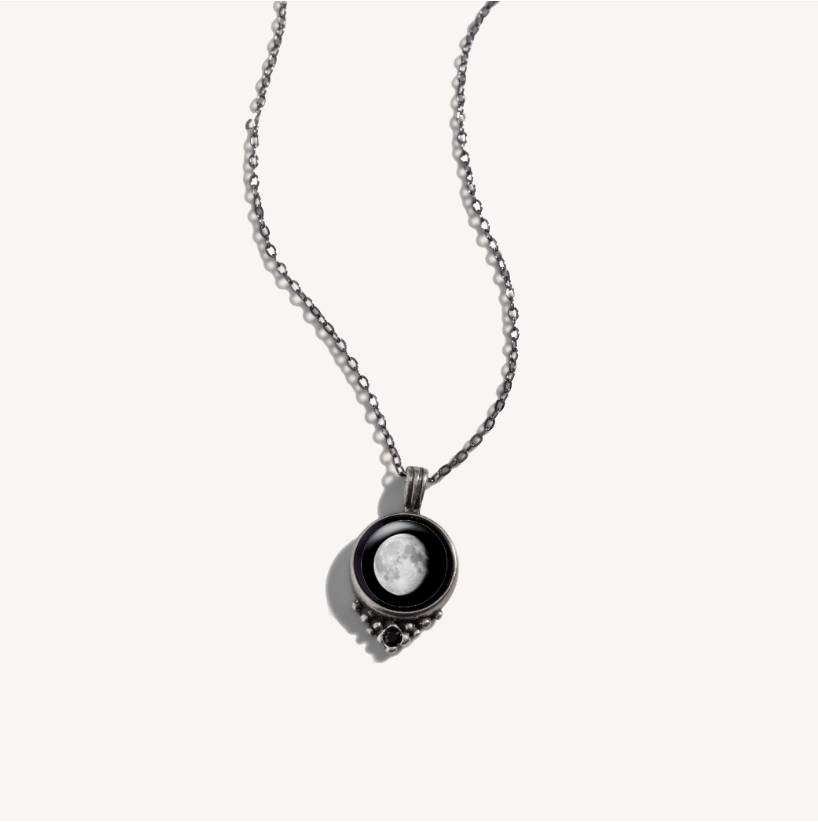 Silver necklace with a round pendant featuring a moon image.