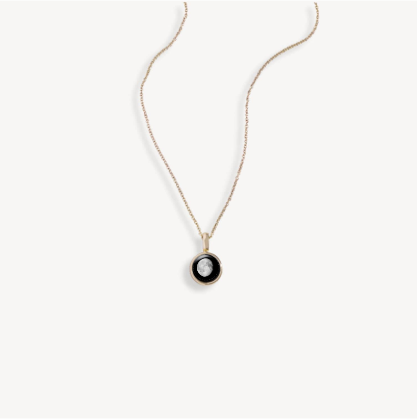 Gold necklace with a round pendant featuring a moon design.