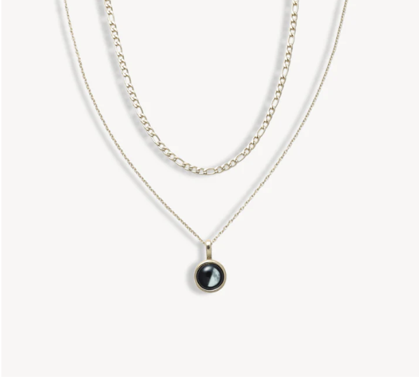 Three layered necklaces with a round black pendant on the bottom chain.
