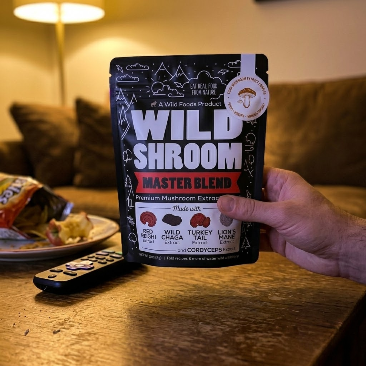 A person holds a black pouch of Wild Shroom Master Blend over a wooden coffee table.