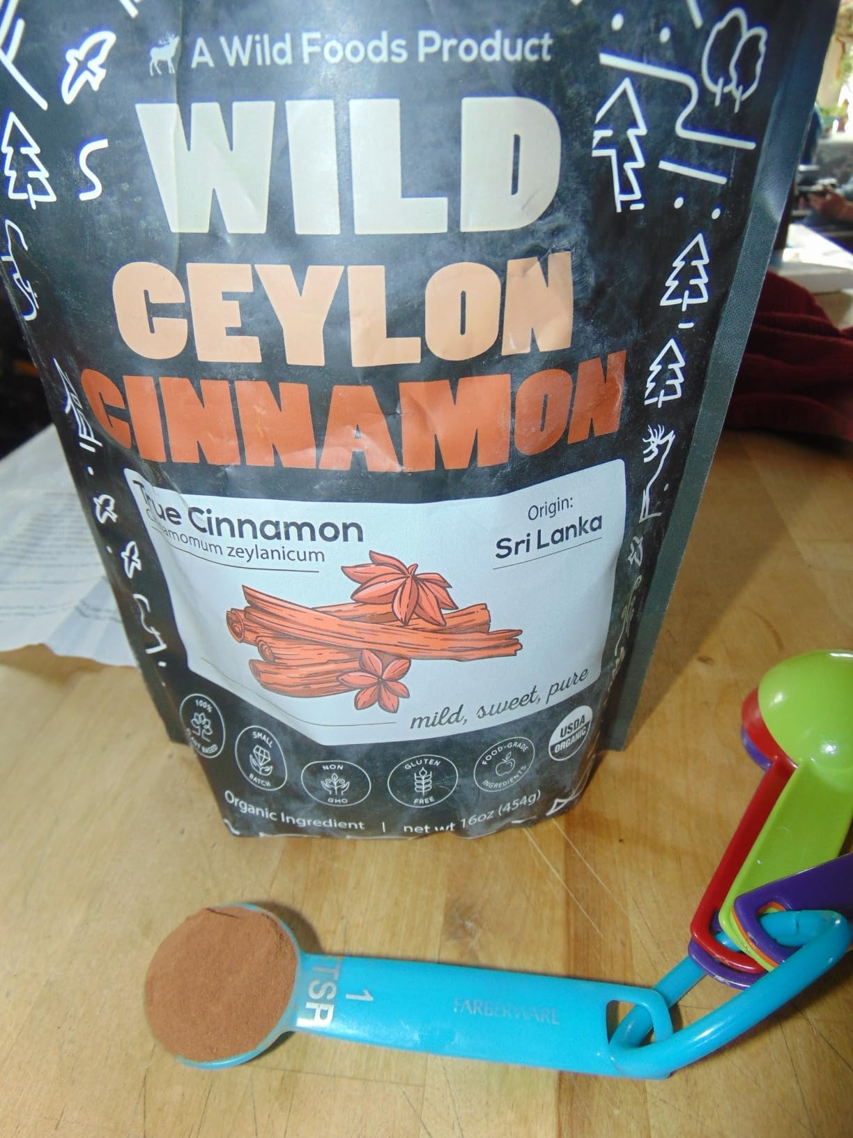 A bag of Wild Ceylon Cinnamon with a teaspoon of the powder in front of it.