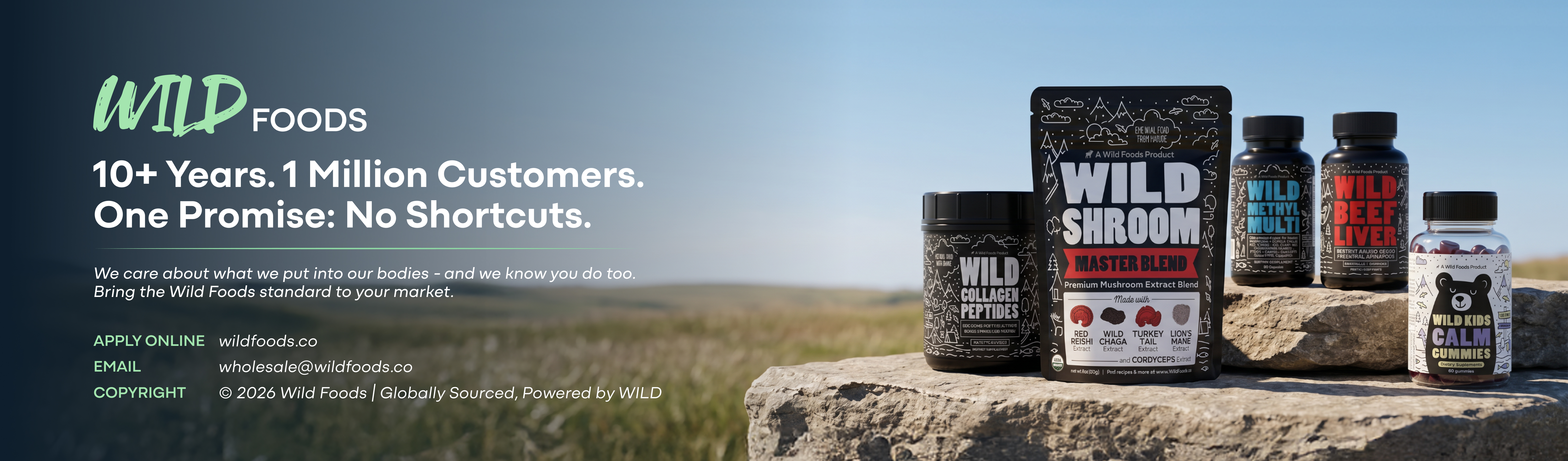 A collection of Wild Foods supplement products displayed on a rock in an open field.