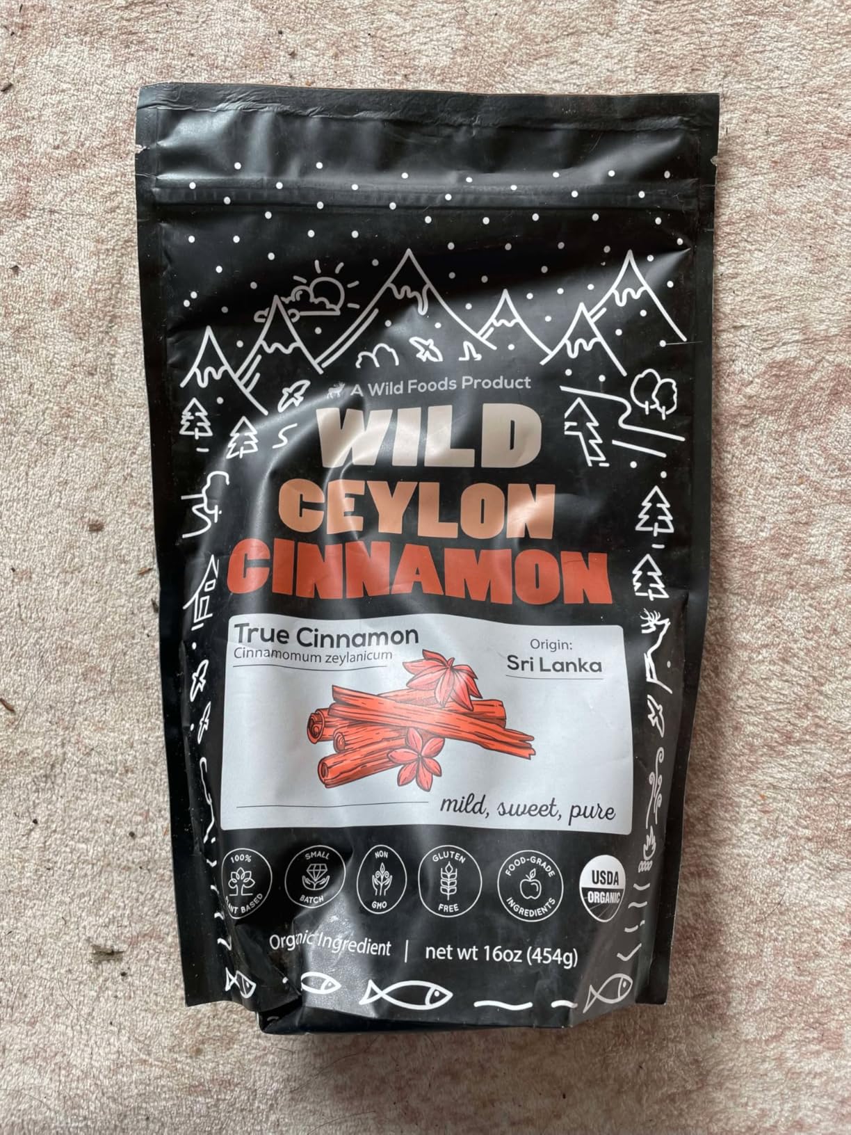 A black pouch of Wild Foods Wild Ceylon Cinnamon, lying on a textured surface.
