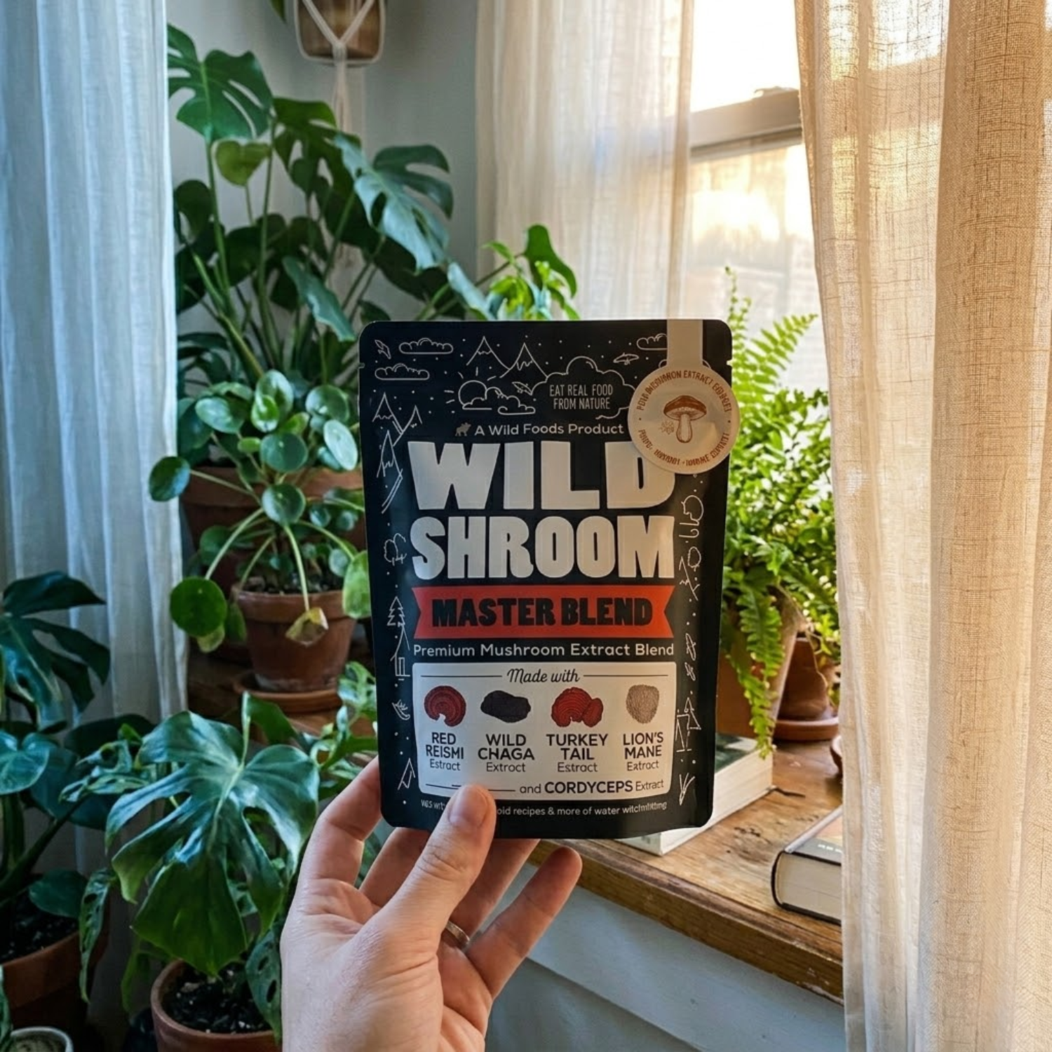 A hand holds a pouch of Wild Shroom Master Blend in front of a sunlit window with houseplants.