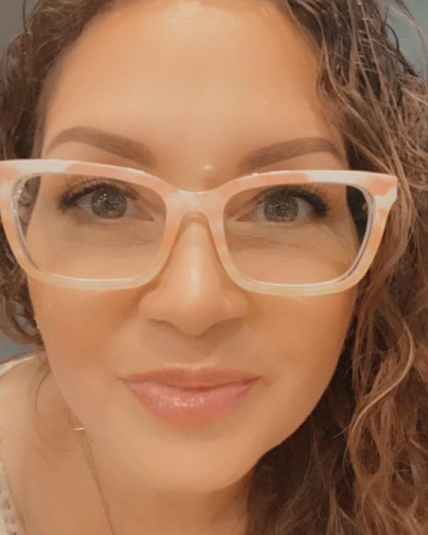 Close-up of a person wearing glasses, smiling.