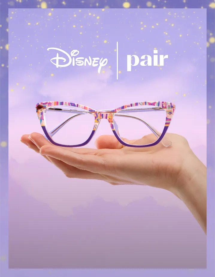Glasses held in a hand with Disney branding on a purple starry background.