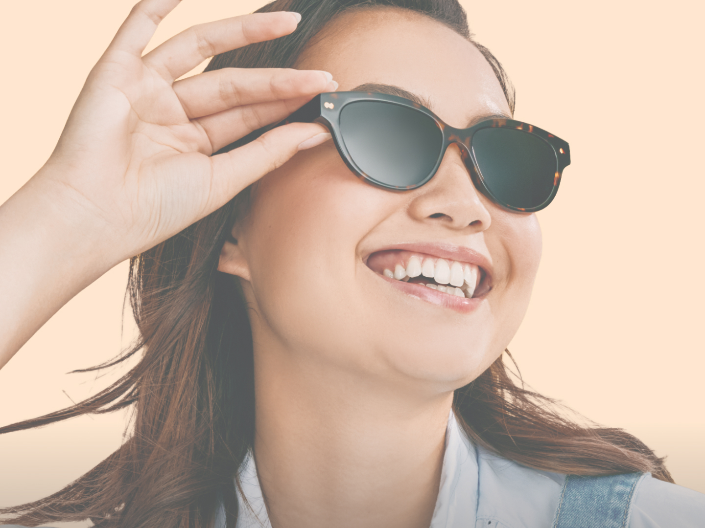 Smiling person wearing sunglasses against a light peach background.
