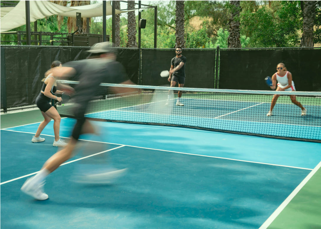 Four people playing pickleball on an outdoor court.