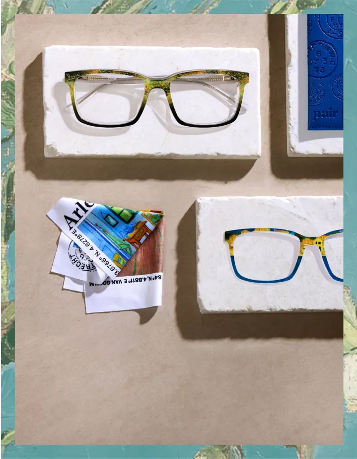 Two pairs of glasses on stone displays with colorful fabric and a blue book.