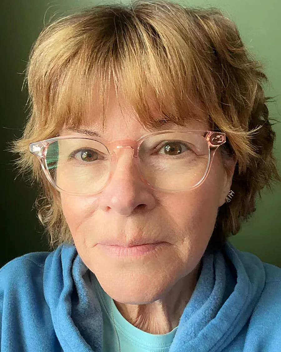 Person with short hair and glasses wearing a blue hoodie.