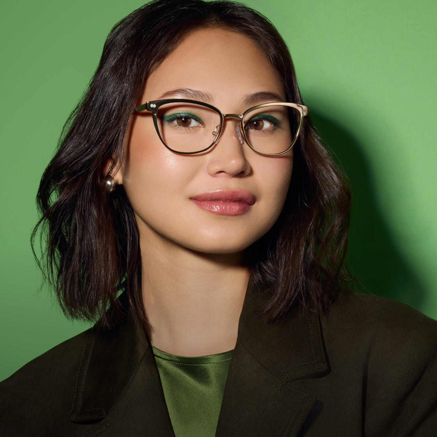 Person with glasses and short hair against a green background.