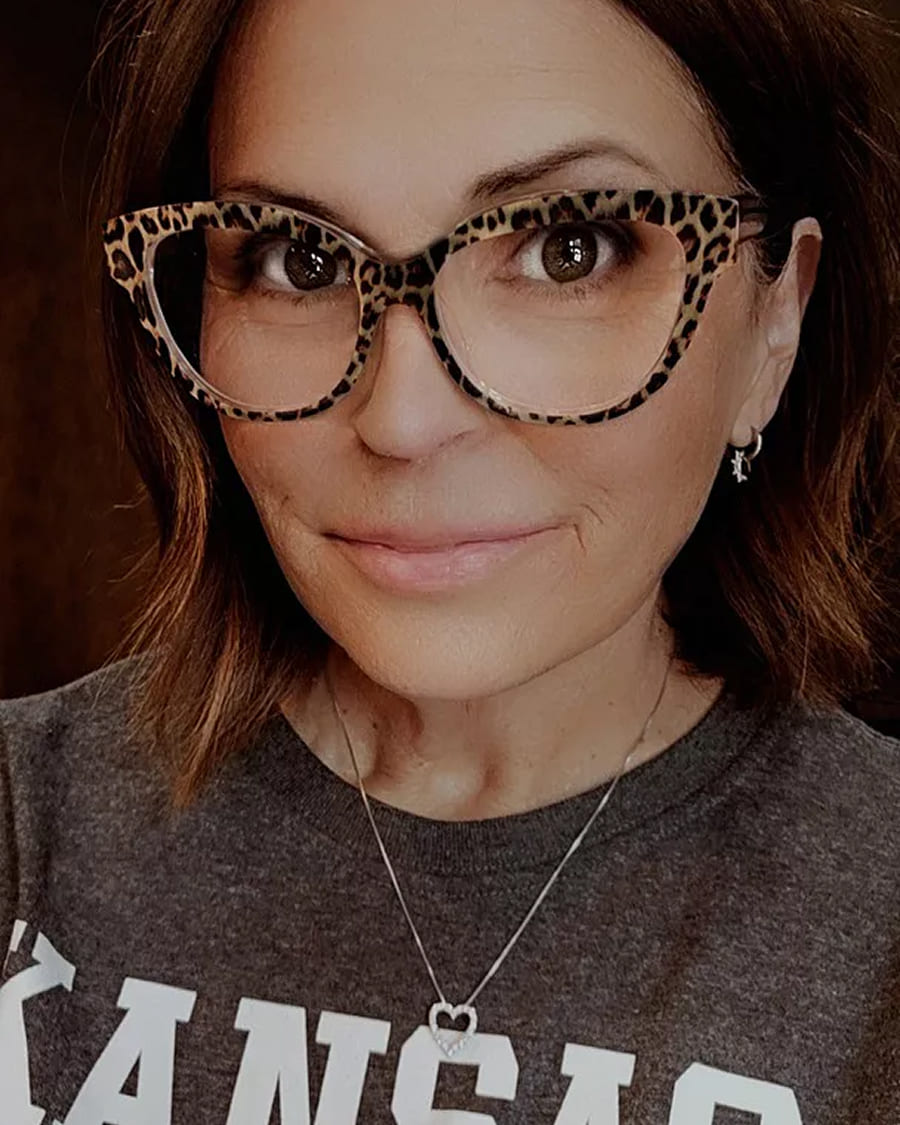 Person wearing leopard-print glasses and a gray shirt with text.