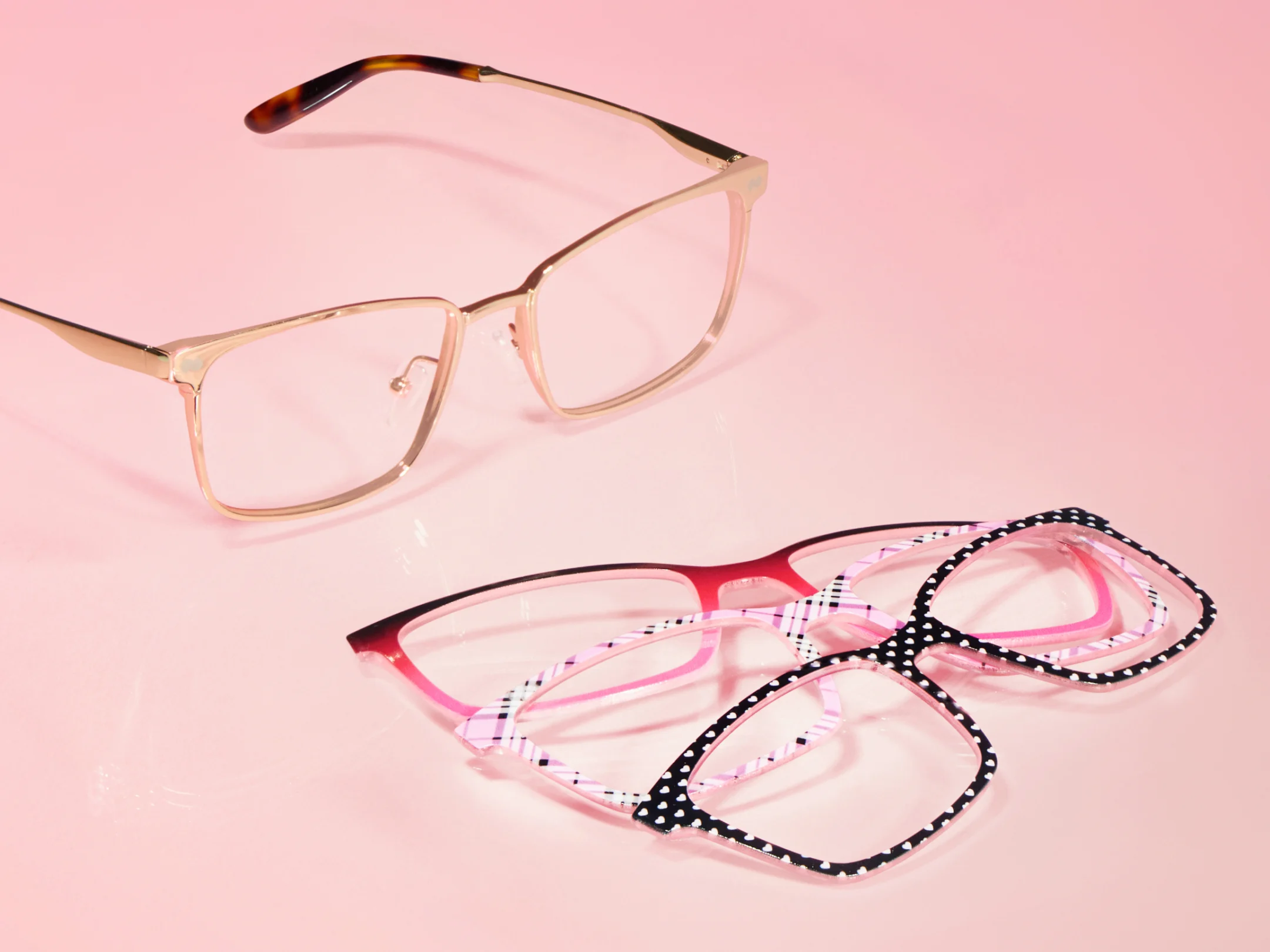 Four pairs of eyeglasses on a pink background.