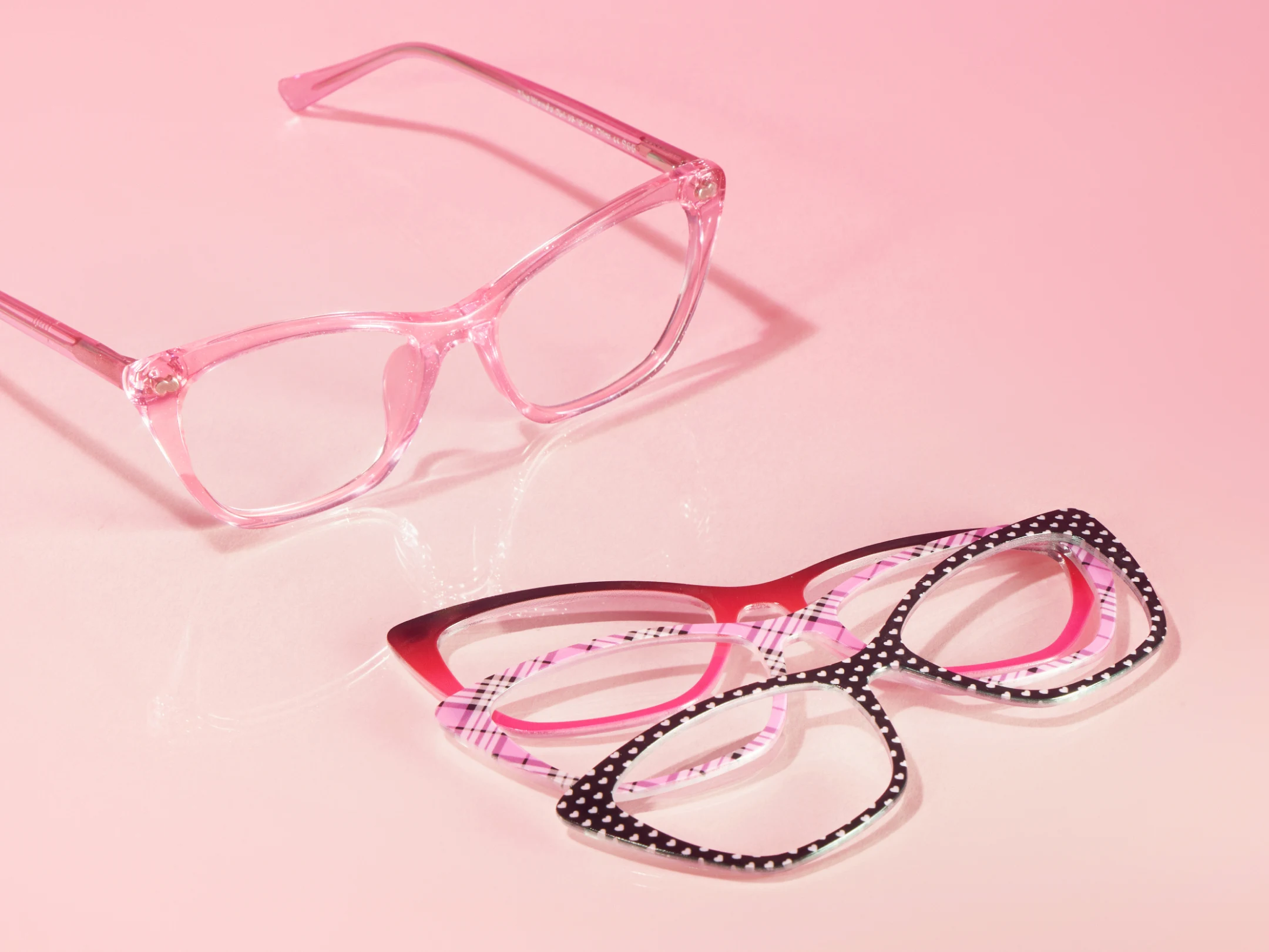 Three pairs of stylish pink eyeglass frames on a pink background.
