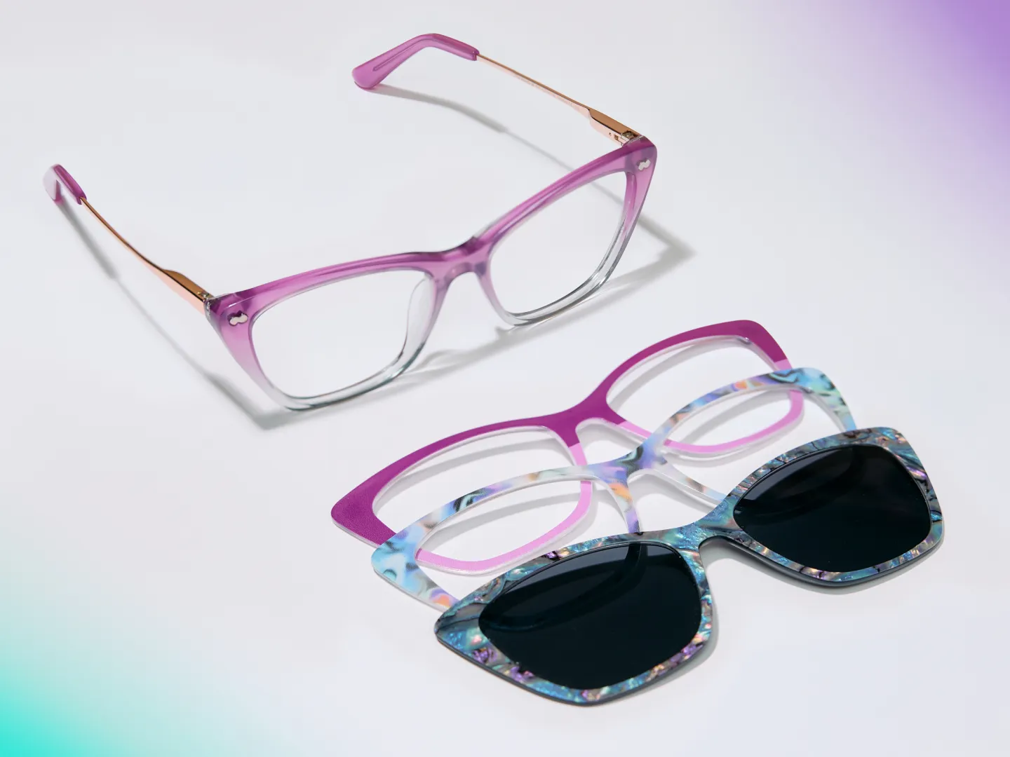 A pair of purple cat-eye glasses with three interchangeable magnetic toppers, including one sunglass frame.