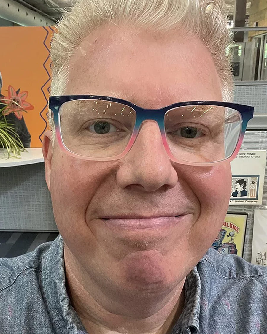 Person with glasses smiling in an indoor setting.