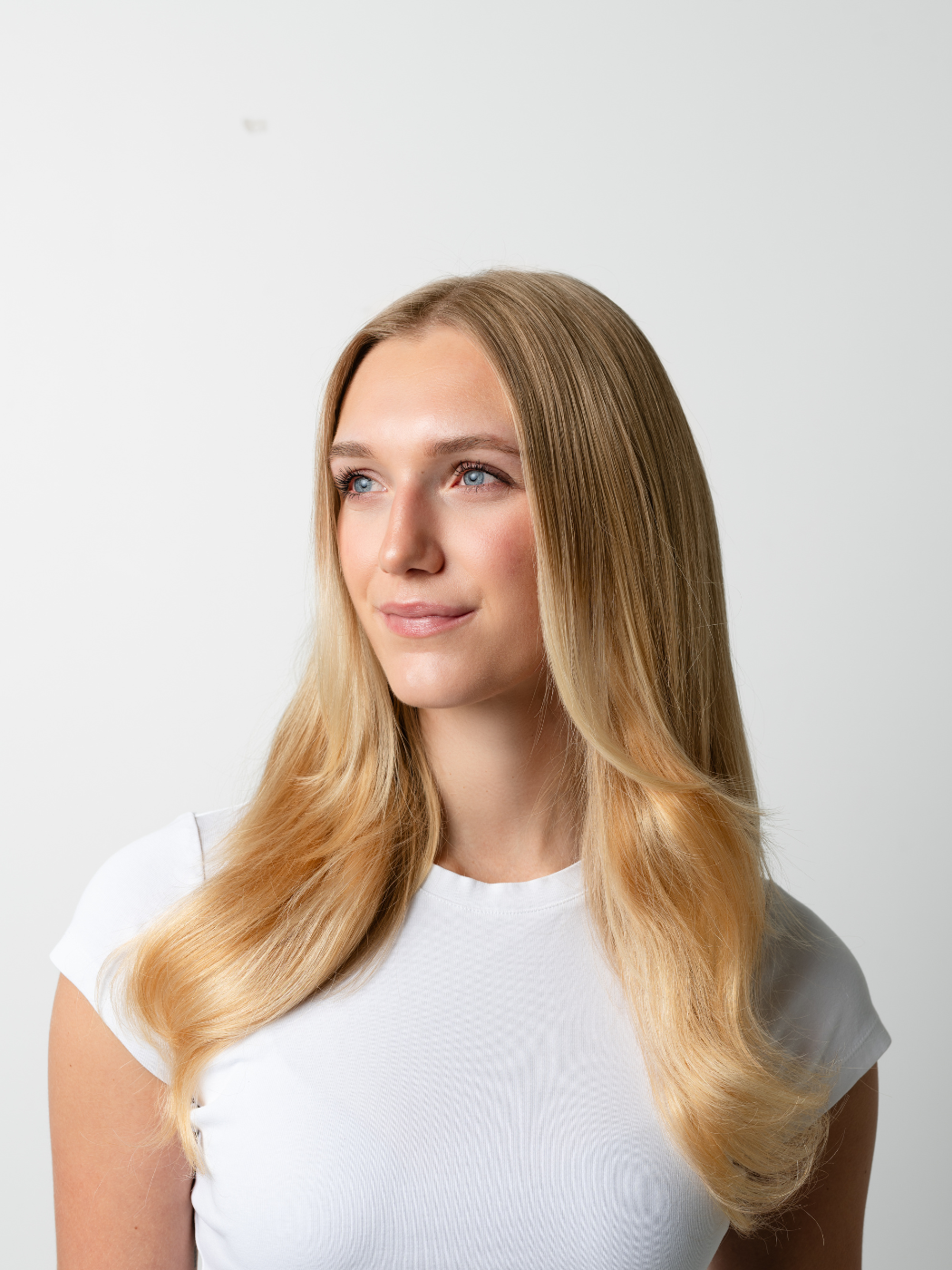 Model with straight blonde hair and face-framing layers looking to the side.