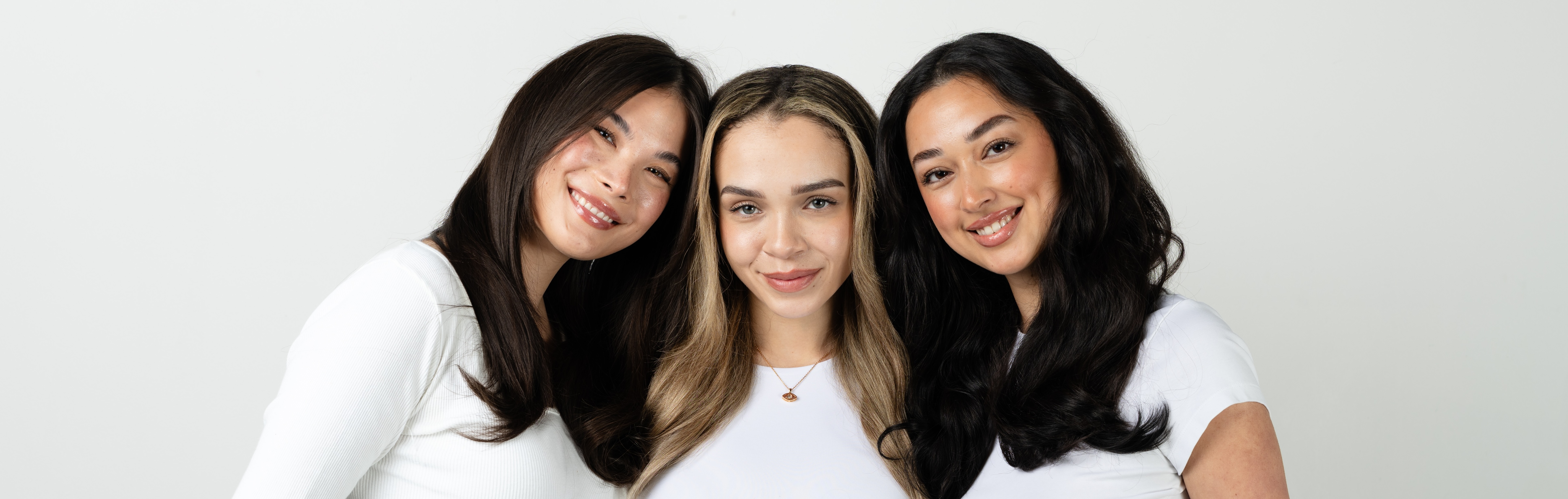 Three hair extensions in different shades on a beige surface with a Cosmopolitan award label.