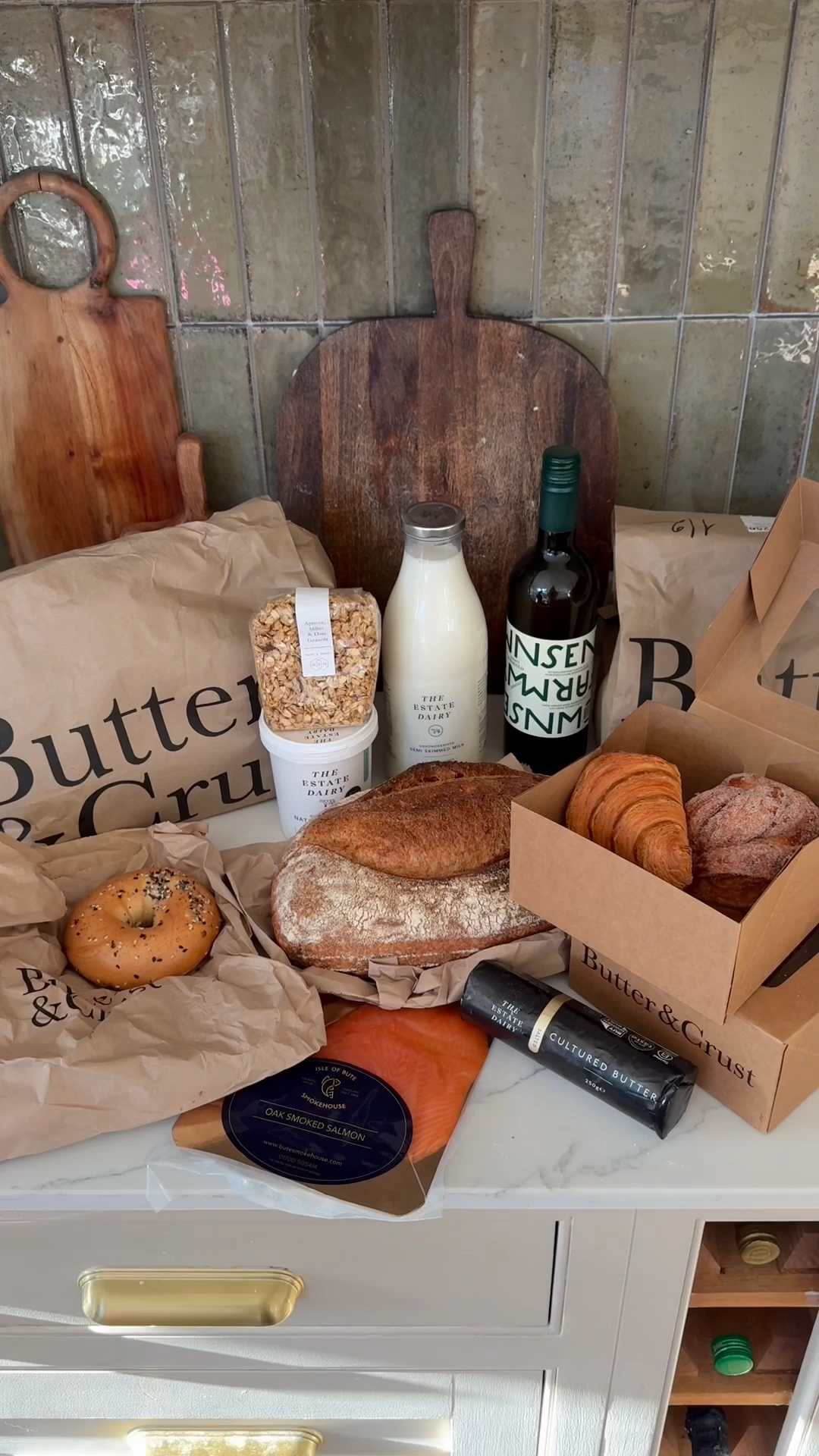 Assorted bakery items, milk, a bottle of drink, and smoked salmon arranged on a kitchen counter.