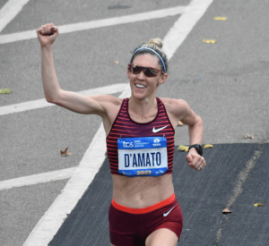 Runner in athletic gear celebrating while crossing a finish line.