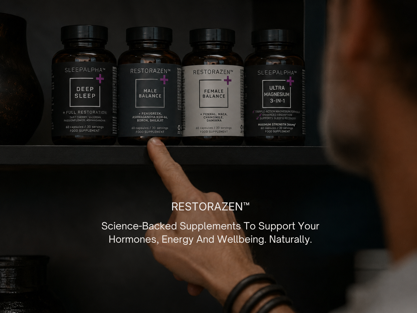 A person's finger pointing to a line of four Restorazen and Sleepalpha supplement bottles on a shelf.