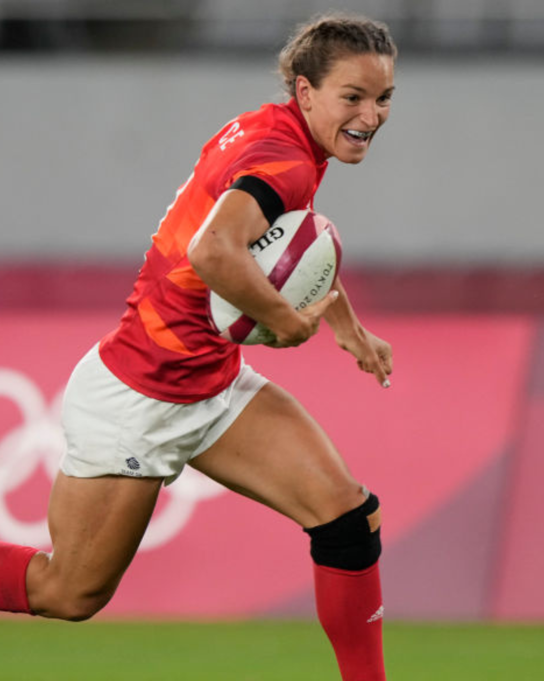 Rugby player in motion, holding the ball during a game.