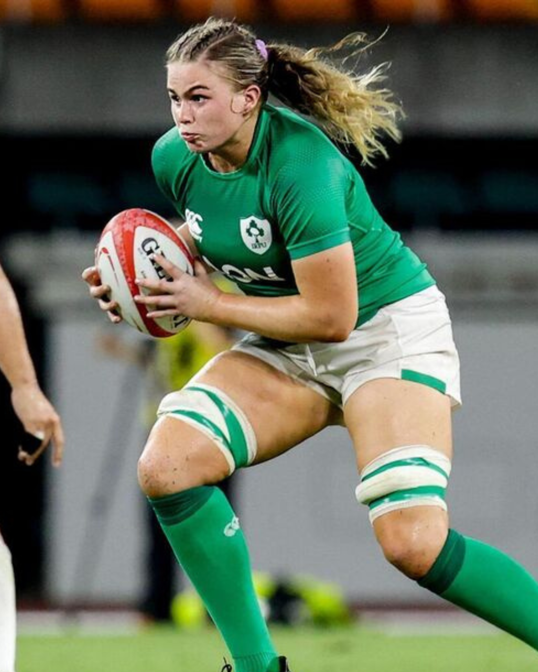 Rugby player in green jersey running with the ball during a match.