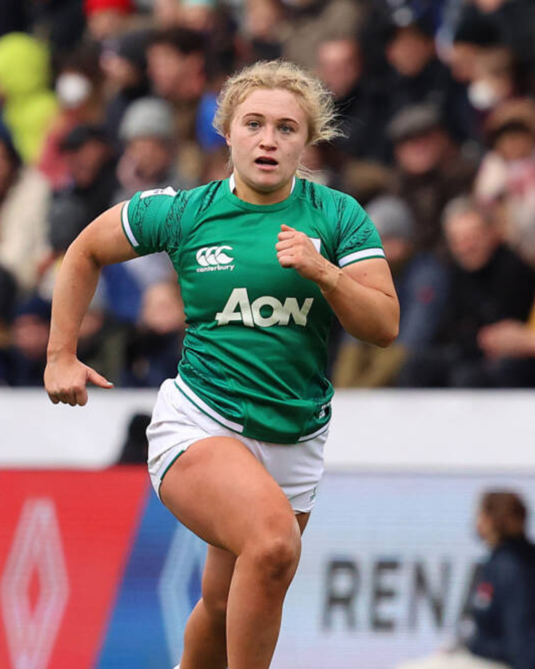 A rugby player in a green jersey running during a match.