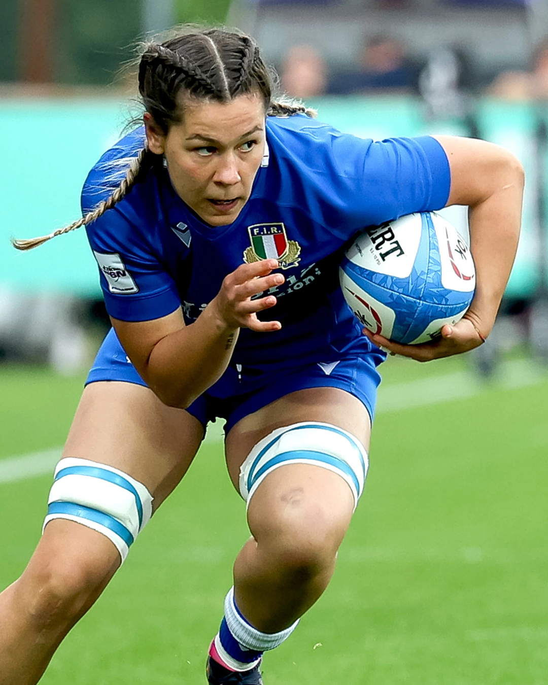 Rugby player in blue uniform running with the ball.