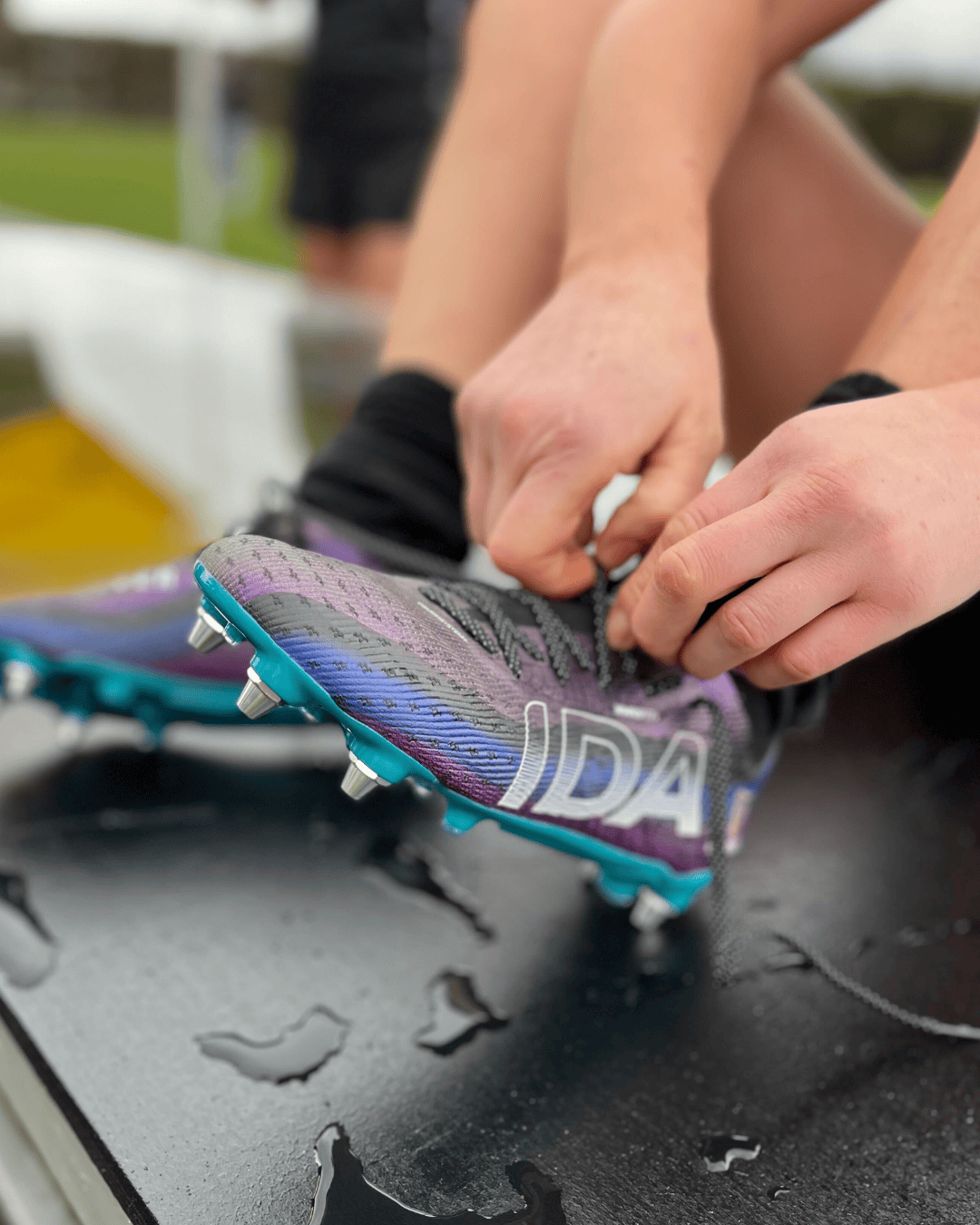 Woman holding a soccer cleat in front of a purple background.