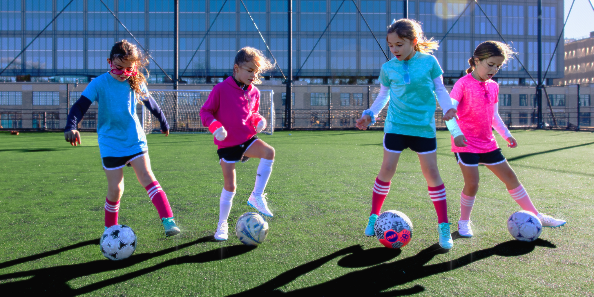 Four young girls playing soccer on a field.