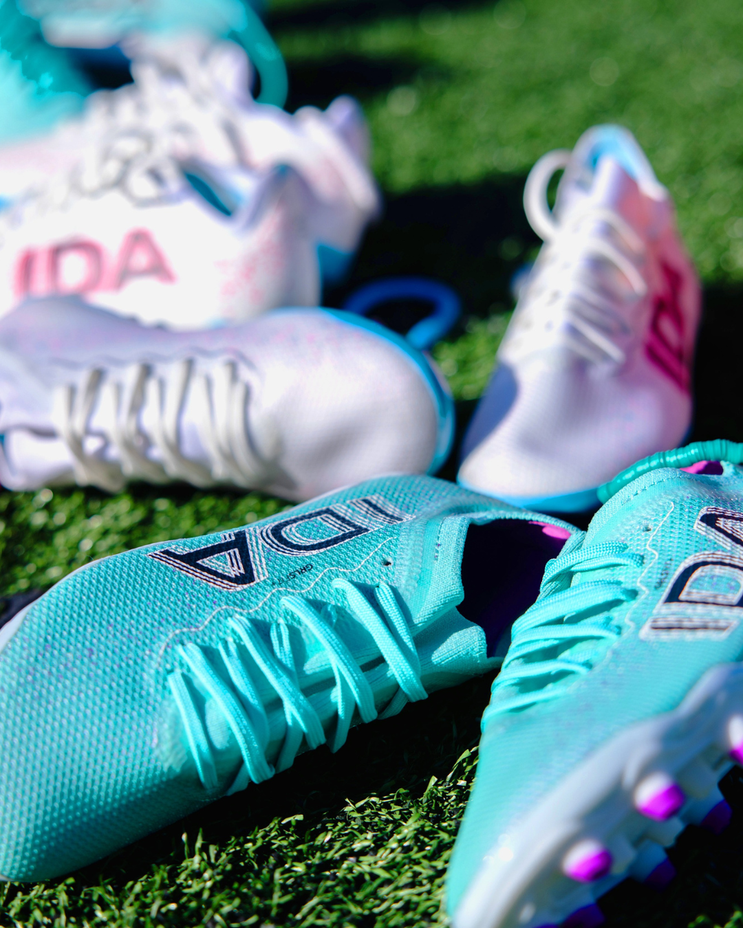 Close-up of turquoise and white soccer cleats on grass.