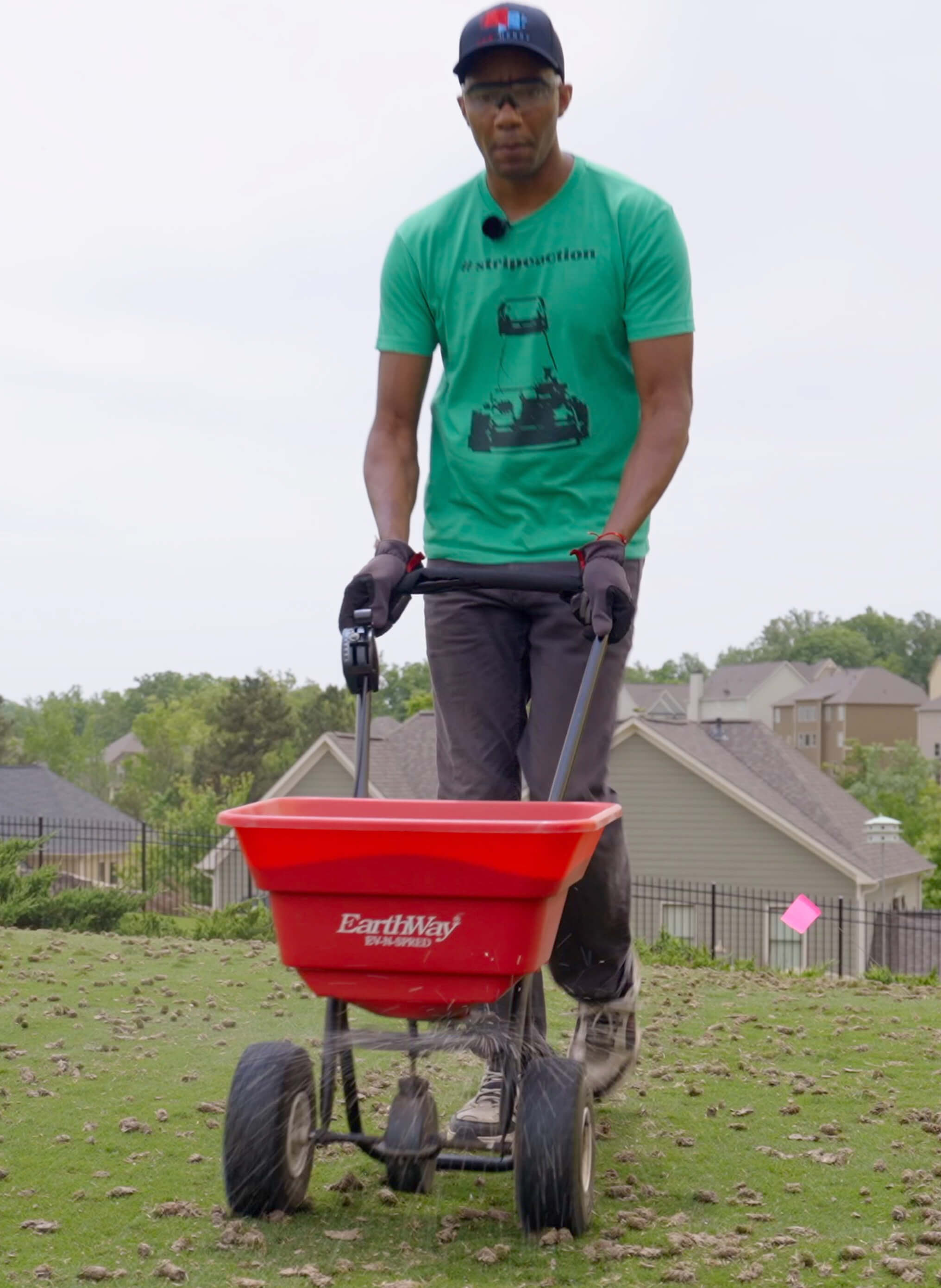 man walking on lawn with broadcast spreader