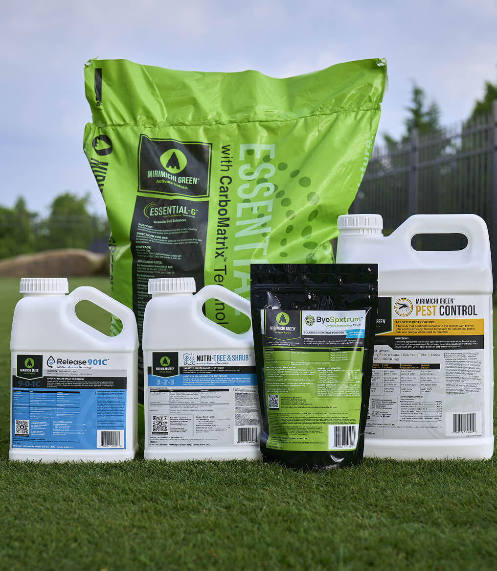 Various garden products on grass, including bottles and a large green bag.