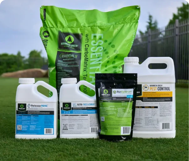 Various lawn care products displayed on grass, including bottles and a large bag.