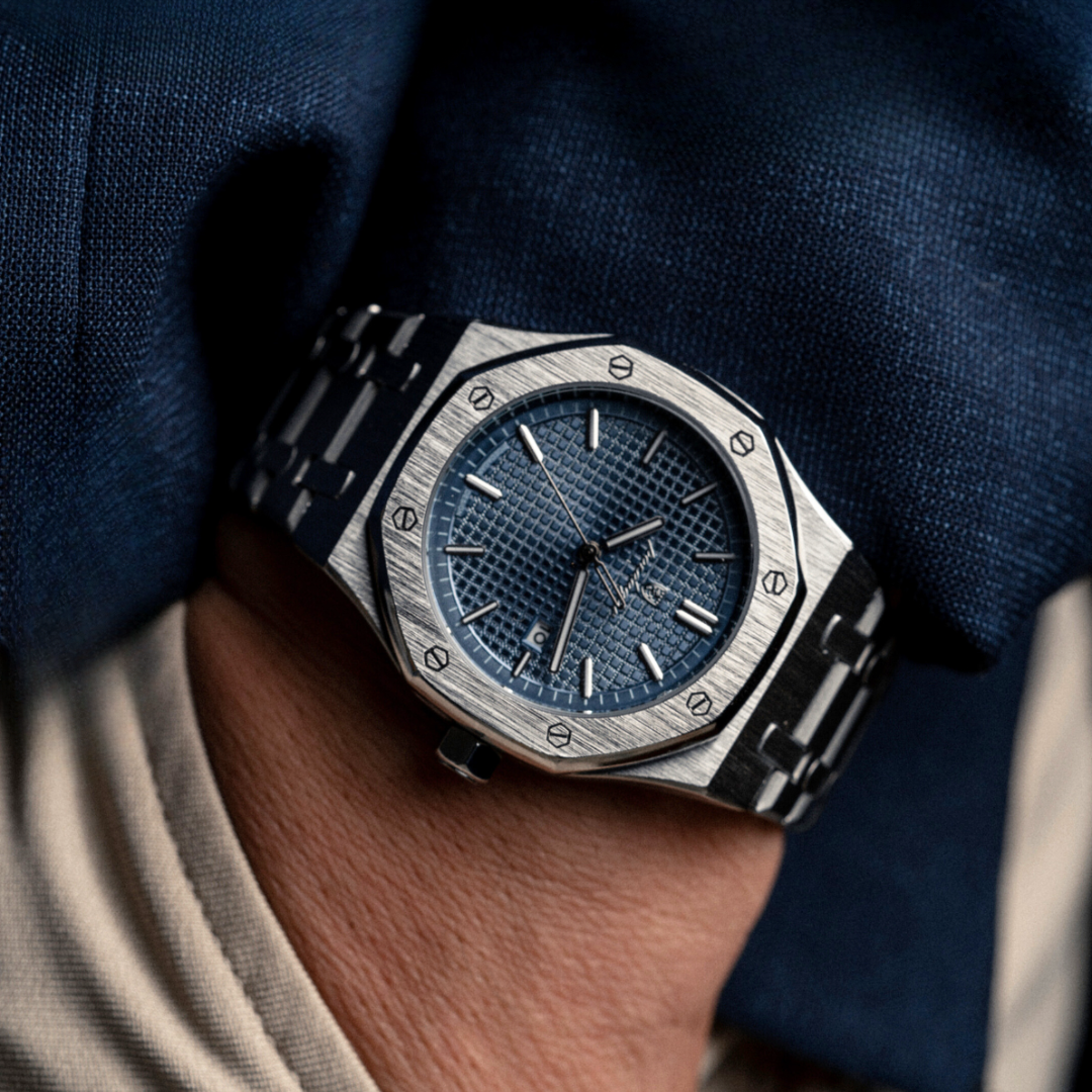 Silver wristwatch with a blue dial and metal bracelet on a wrist.