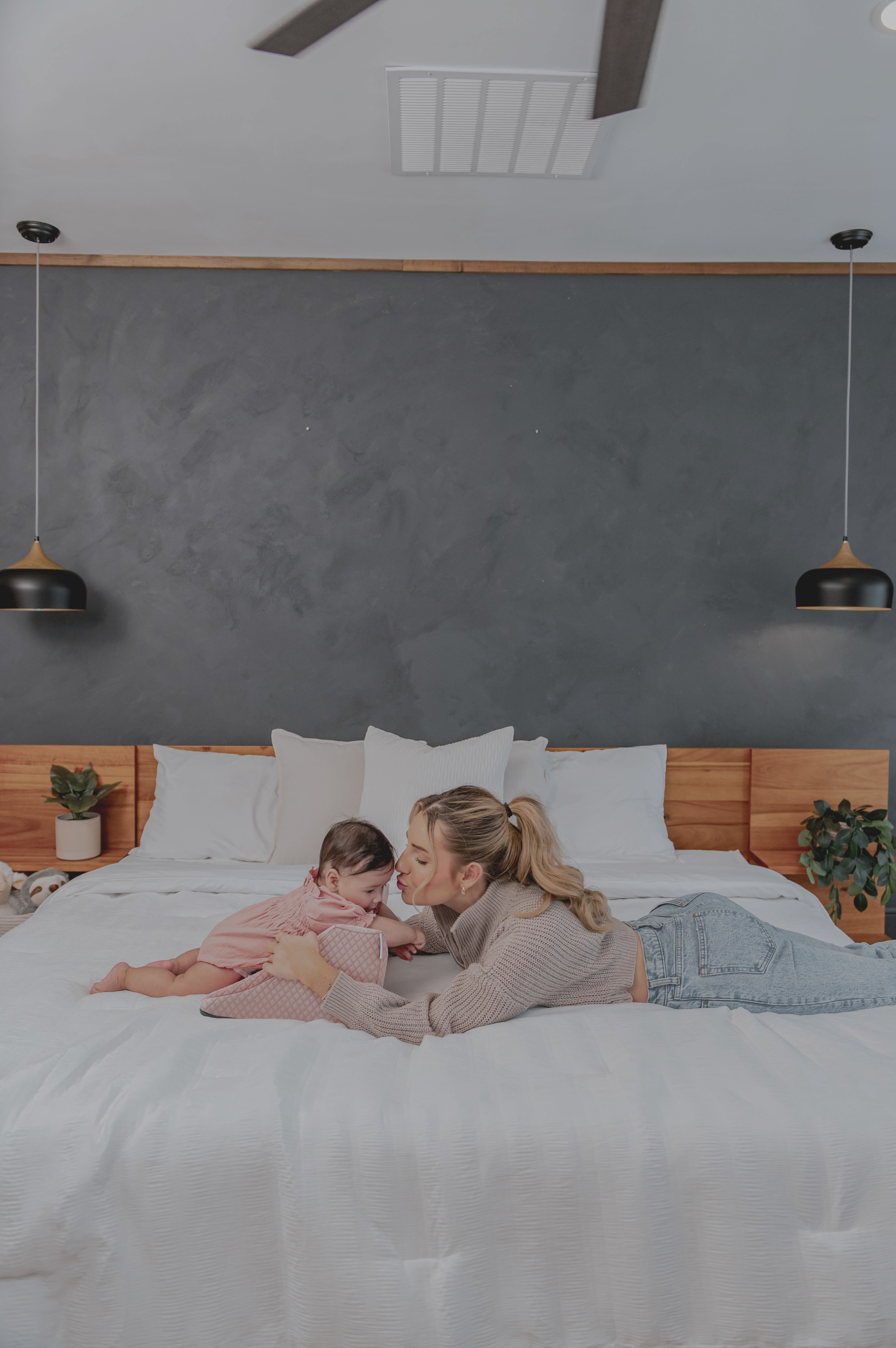Woman and baby lying on a bed in a cozy room.