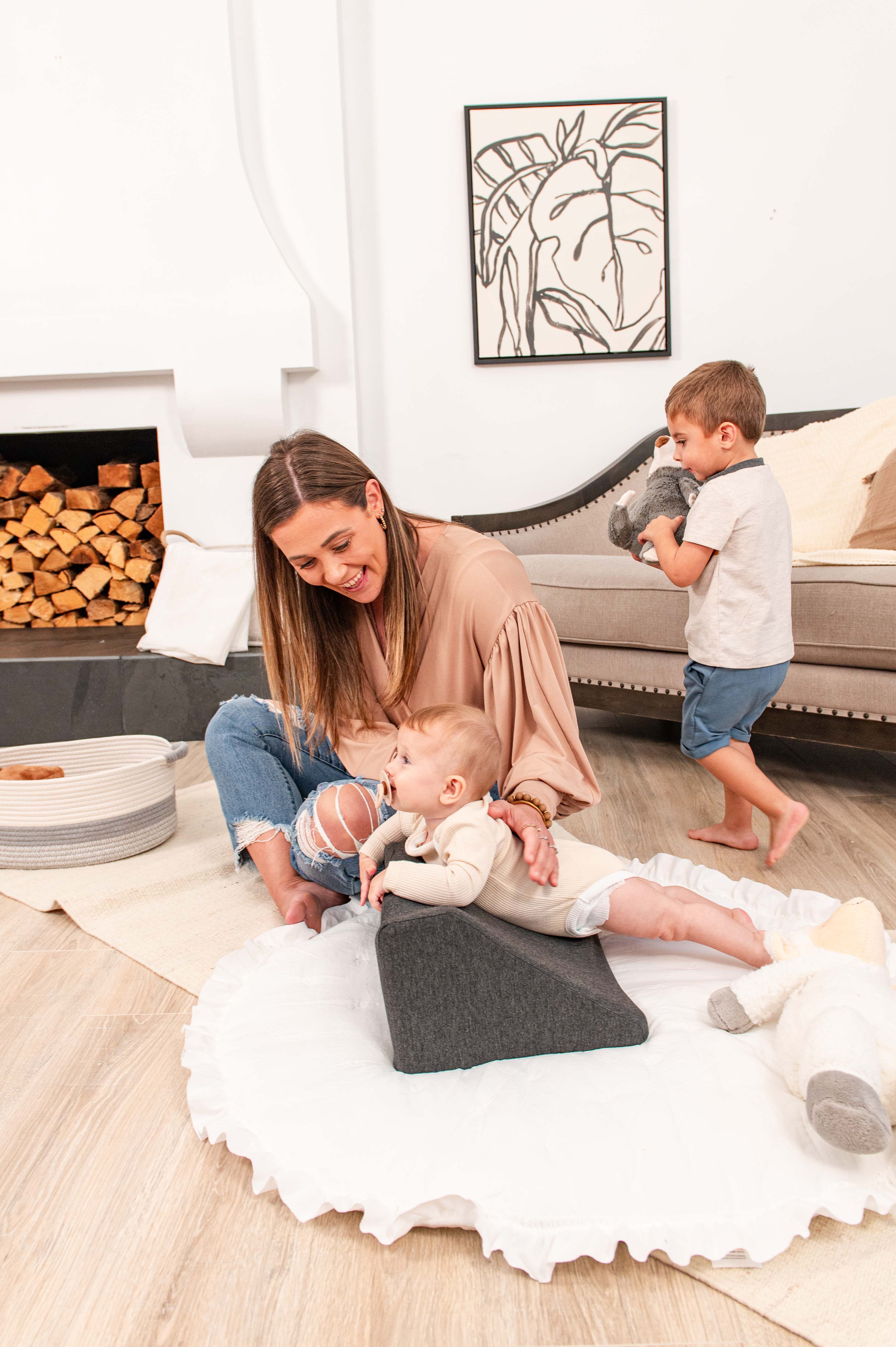 Woman with two children playing on the floor in a cozy living room.