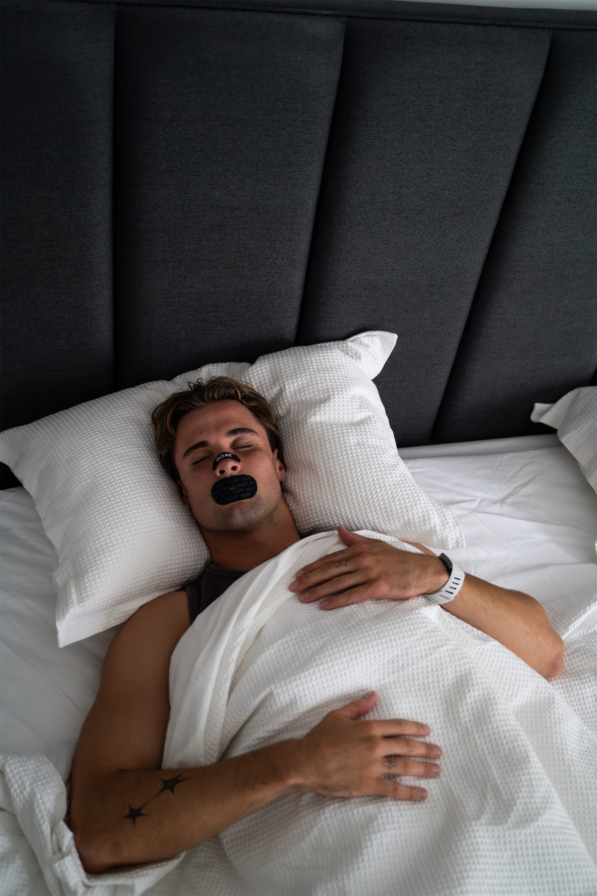 Person sleeping in bed with adhesive strip on mouth.